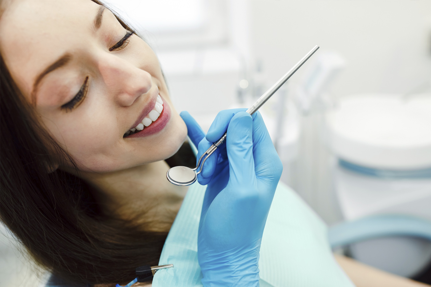 Paciente sonriendo durante una atención dental con dentista sosteniendo espejo bucal
