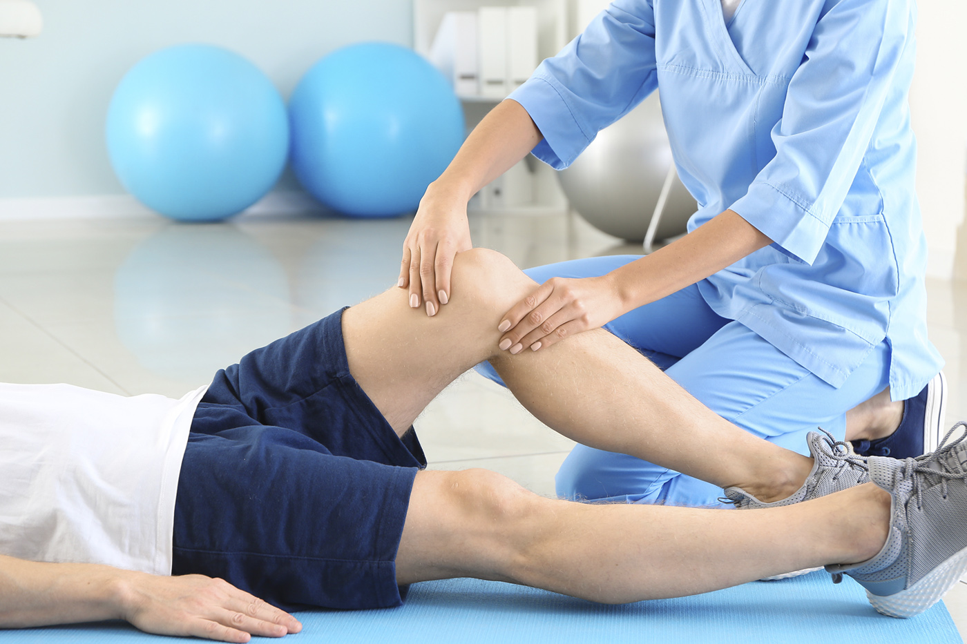 Kinesióloga realizando terapia de rehabilitación de rodilla a un paciente